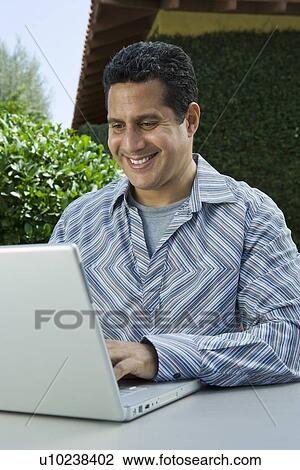 Stock Image - Man using laptop in back yard. Fotosearch