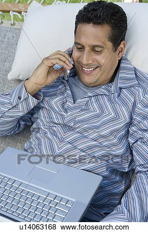 Man using mobile phone and laptop in hammock View Large Photo Image Stock Photo - Man using mobile phone and laptop in hammock. Fotosearch