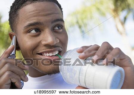 Man using mobile phone while drinking milk shake View Large Photo Image Stock Photo - Man using mobile phone while drinking milk shake. Fotosearch