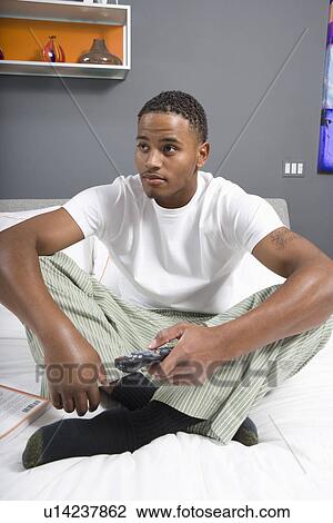 Stock Image - Man Watching TV in Bedroom. Fotosearch