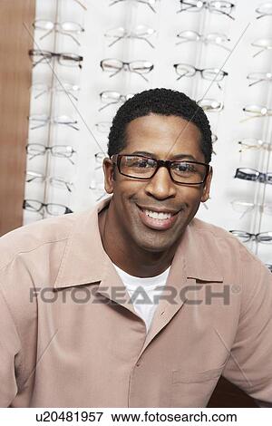 Stock Photo - Man wearing glasses at opticians, portrait. Fotosearch