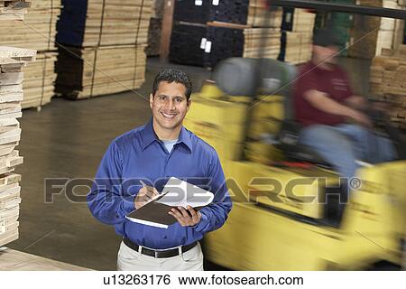 Man with clipboard in front of forklift in warehouse View Large Photo Image Stock Photograph - Man with clipboard in front of forklift in warehouse. Fotosearch