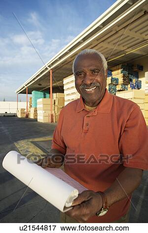 Man with clipboard outside warehouse full of wood View Large Photo Image Stock Photo - Man with clipboard outside warehouse full of wood. Fotosearch