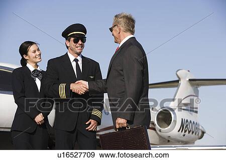 Mid-adult airline pilot and senior businessman shaking hands. View Large Photo Image Stock Photo - Mid-adult airline pilot and senior businessman shaking hands.. Fotosearch