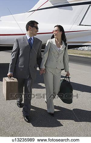 Mid-adult Asian business couple walking in front of airplane. View Large Photo Image Stock Photo - Mid-adult Asian business couple walking in front of airplane.. Fotosearch
