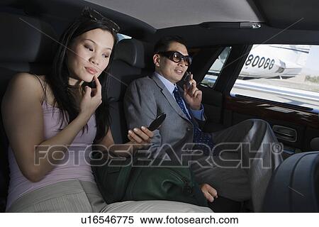 Stock Photography - Mid-adult Asian businessman and businesswoman inside limousine.. Fotosearch