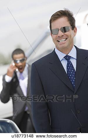 Stock Photo - Mid-adult businessman in sunglasses smiling.. Fotosearch