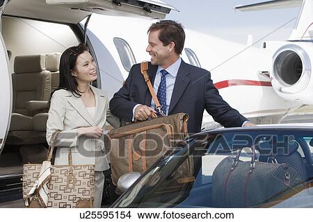 Picture - Mid-adult businesswoman and businessman getting in car.. Fotosearch