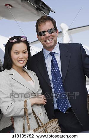 Mid-adult businesswoman and businessman standing in front of airplane. View Large Photo Image Stock Image - Mid-adult businesswoman and businessman standing in front of airplane.. Fotosearch