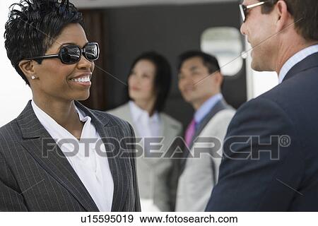 Stock Photo - Mid-adult businesswoman and businessman talking.. Fotosearch