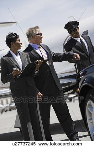 Stock Photography - Mid-adult businesswoman, senior businessman and chauffeur in front of car.. Fotosearch