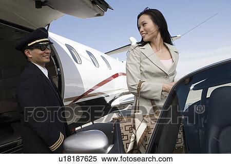Stock Photography - Mid-adult businesswoman turning back on pilot and smiling.. Fotosearch