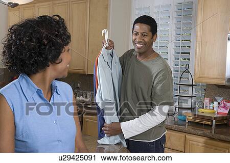 Mid-adult couple at domestic kitchen, man holding clothes View Large Photo Image Stock Image - Mid-adult couple at domestic kitchen, man holding clothes. Fotosearch