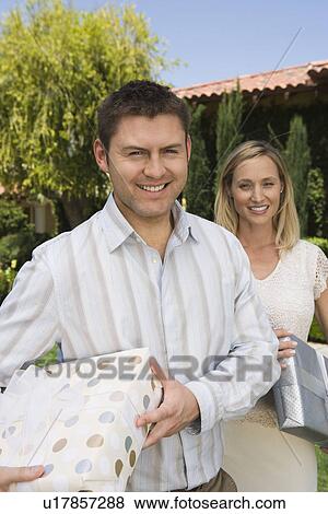 Stock Photo - Mid-adult couple holding birthday presents, smiling. Fotosearch