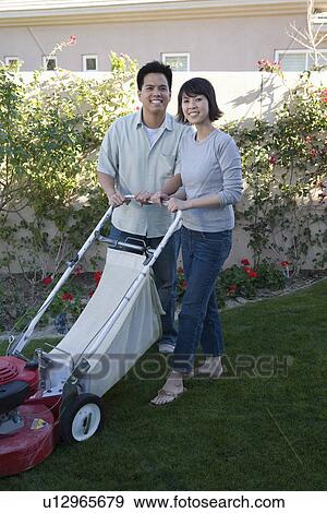 Mid-adult couple mowing lawn, smiling View Large Photo Image Stock Photo - Mid-adult couple mowing lawn, smiling. Fotosearch