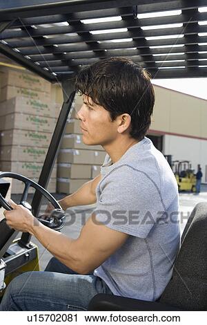 Mid-adult man driving forklift View Large Photo Image Stock Image - Mid-adult man driving forklift. Fotosearch