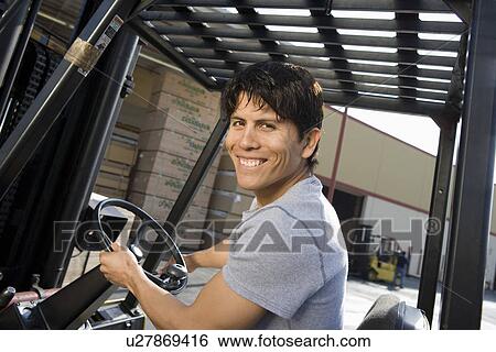 Stock Photograph - Mid-adult man driving forklift. Fotosearch