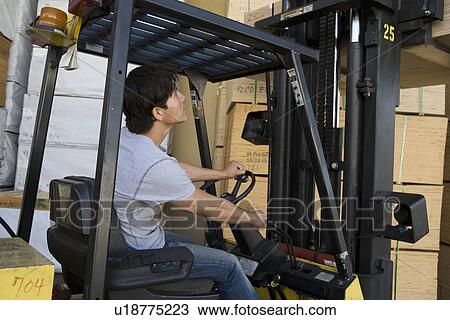 Stock Image - Mid-adult man driving forklift truck. Fotosearch
