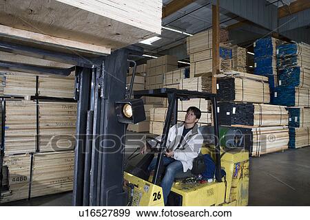 Stock Photo - Mid-adult man driving forklift truck. Fotosearch
