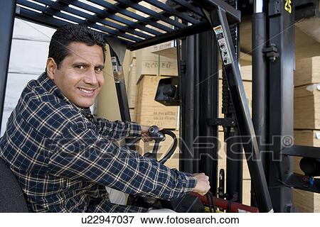 Stock Photo - Mid-adult man driving forklift truck. Fotosearch