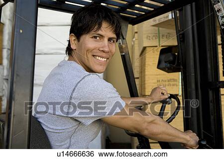 Stock Photograph - Mid-adult man driving forklift truck. Fotosearch