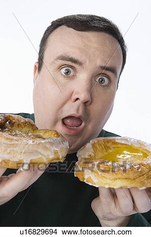 Mid-adult man holding pastry View Large Photo Image Picture - Mid-adult man holding pastry. Fotosearch