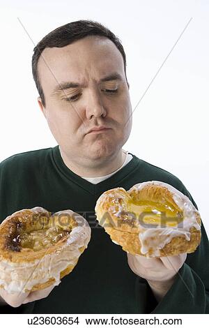 Picture - Mid-adult man holding pastry. Fotosearch