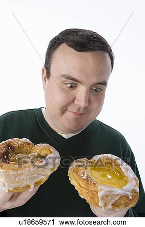 Stock Image - Mid-adult man holding pastry. Fotosearch
