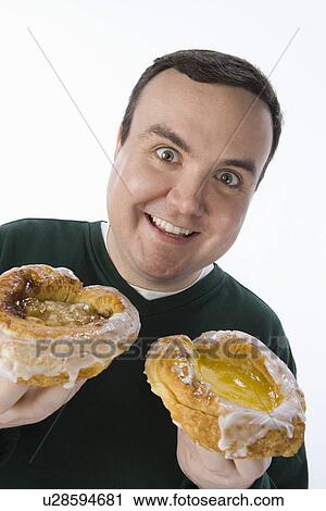 Stock Image - Mid-adult man holding pastry. Fotosearch