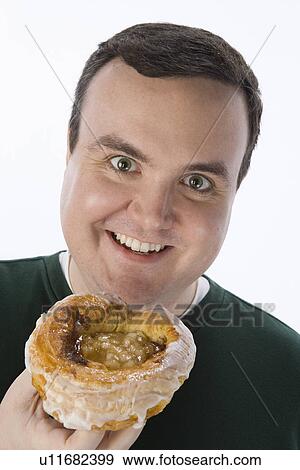 Stock Photo - Mid-adult man holding pastry. Fotosearch