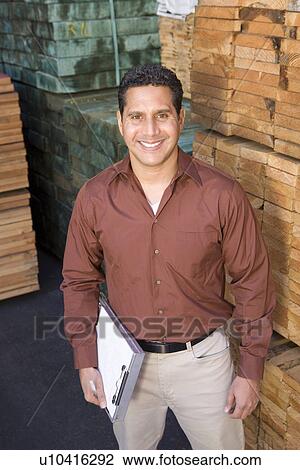 Stock Image - Mid-adult man stock-taking in warehouse. Fotosearch