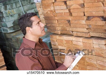 Stock Image - Mid-adult man stock-taking in warehouse. Fotosearch