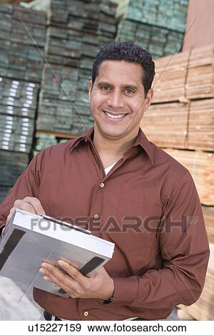 Stock Photo - Mid-adult man stock-taking in warehouse. Fotosearch