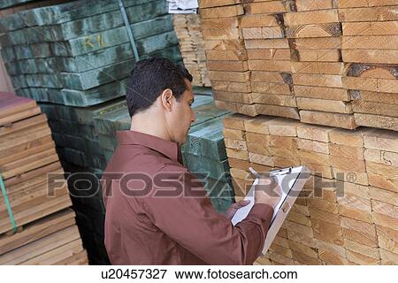 Stock Photo - Mid-adult man stock-taking in warehouse. Fotosearch