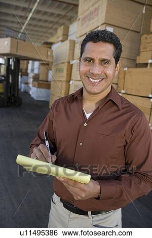Stock Photograph - Mid-adult man stock-taking in warehouse. Fotosearch