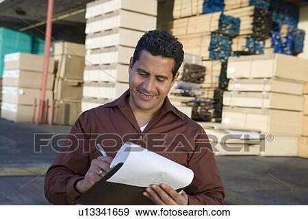 Mid-adult man with clipboard outside warehouse full of wood View Large Photo Image Stock Photo - Mid-adult man with clipboard outside warehouse full of wood. Fotosearch