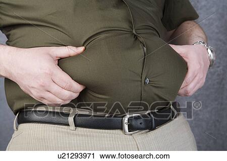 Stock Image - Mid-adult man with hands on belly, mid section. Fotosearch