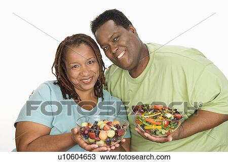 Mid-adult overweight woman and mid-adult overweight man holding bowls with fruit and vegetable salad, smiling View Large Photo Image Stock Image - Mid-adult overweight woman and mid-adult overweight man holding bowls with fruit and vegetable salad, smiling. Fotosearch