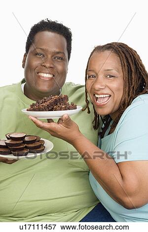 Mid-adult overweight woman and mid-adult overweight man holding plates with cookies View Large Photo Image Stock Photo - Mid-adult overweight woman and mid-adult overweight man holding plates with cookies. Fotosearch