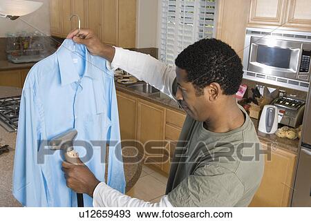 Mid-adult woman cleaning shirt in domestic kitchen View Large Photo Image Stock Image - Mid-adult woman cleaning shirt in domestic kitchen. Fotosearch