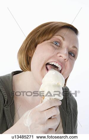 Stock Image - Mid-adult woman eating ice cream, portrait. Fotosearch