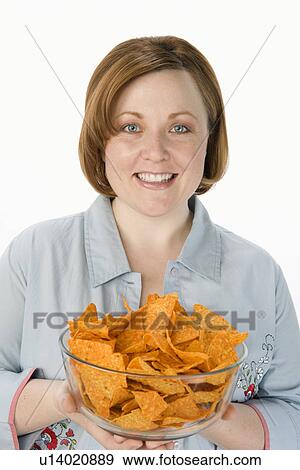Stock Photo - Mid-adult woman holding bowl of potato chips. Fotosearch