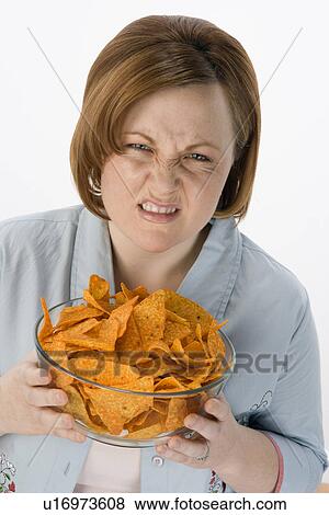 Stock Photo - Mid-adult woman holding bowl of potato chips. Fotosearch