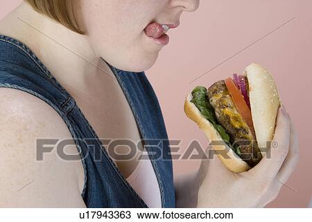 Mid-adult woman holding hamburger View Large Photo Image Stock Image - Mid-adult woman holding hamburger. Fotosearch