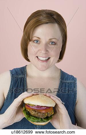 Mid-adult woman holding hamburger View Large Photo Image Stock Photo - Mid-adult woman holding hamburger. Fotosearch