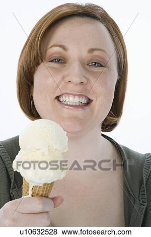 Stock Photo - Mid-adult woman holding ice cream cone, portrait. Fotosearch