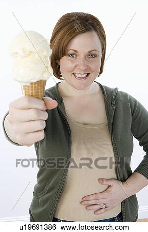 Stock Photograph - Mid-adult woman holding ice cream cone, portrait. Fotosearch