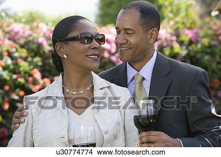 Picture - Middle-aged couple with wine in garden. Fotosearch