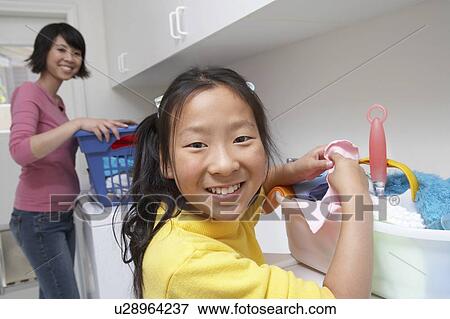 Stock Photo - Mother and daughter (7-9) doing laundry. Fotosearch