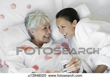 Mother and daughter with mobile phone on bed View Large Photo Image Stock Image - Mother and daughter with mobile phone on bed. Fotosearch